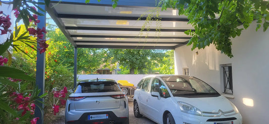 carport aluminium abritant deux voitures sur le côté d'une maison par une journée ensoleillée