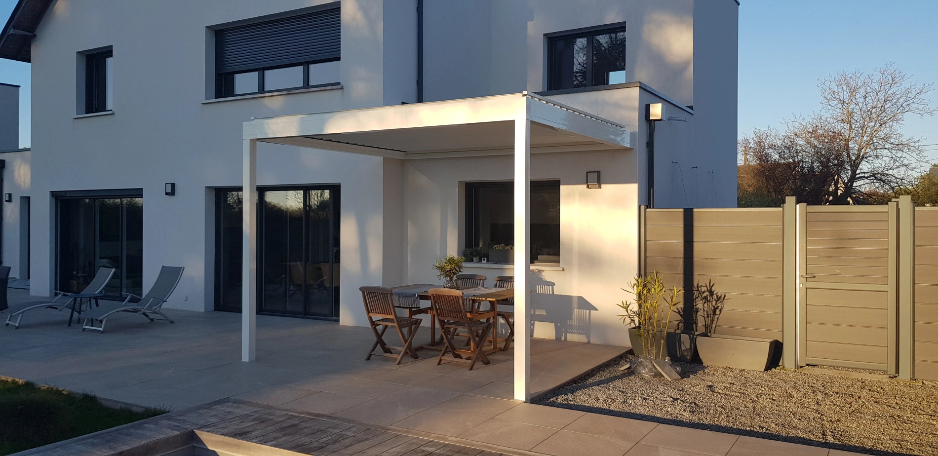 pergola bioclimatique sur mesure adossée maison moderne grande terrasse dalles sur plots