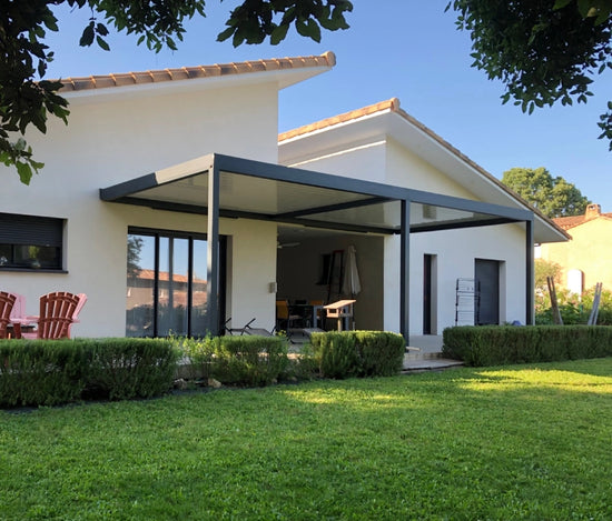 pergola bioclimatique adossée à une maison style basque face à une grand jardin verdoyant