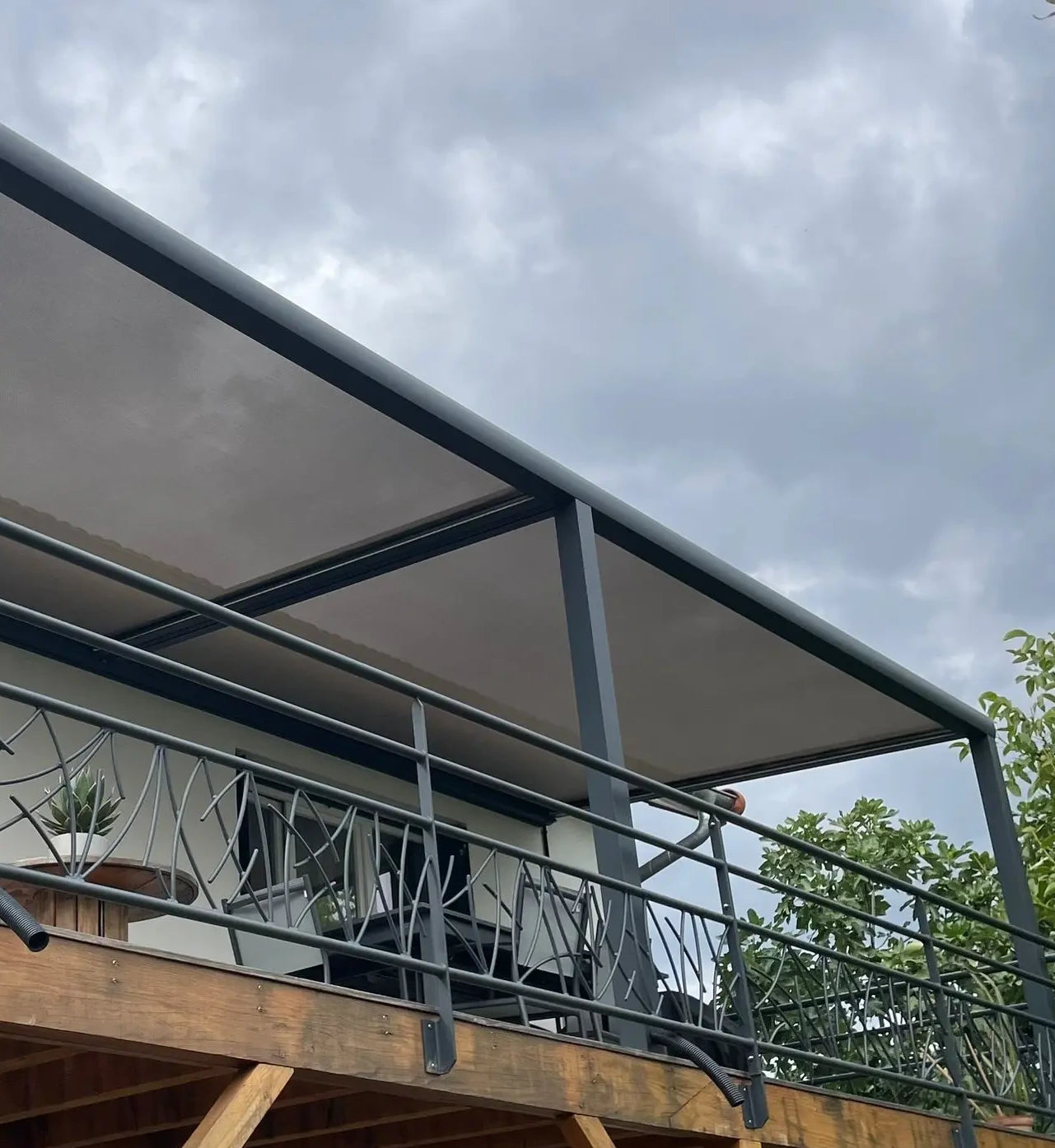 Pergola toile rétractable sur mesure installée sur terrasse bois sur pilotis avec toile dickson microperforée